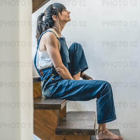 A woman doing stretching exercises on the stairs of her home. Wellbeing concept