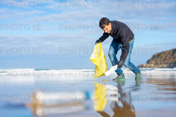 Volunteer man collecting garbage or plastic on the beach. Ecology concept