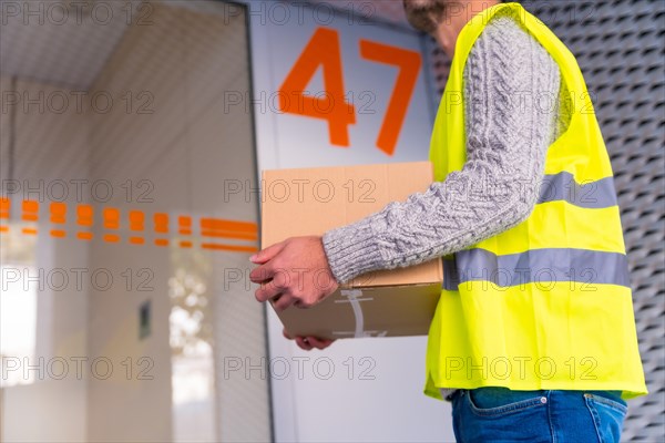 A young delivery man in a protective uniform at the delivery of the online order in a home