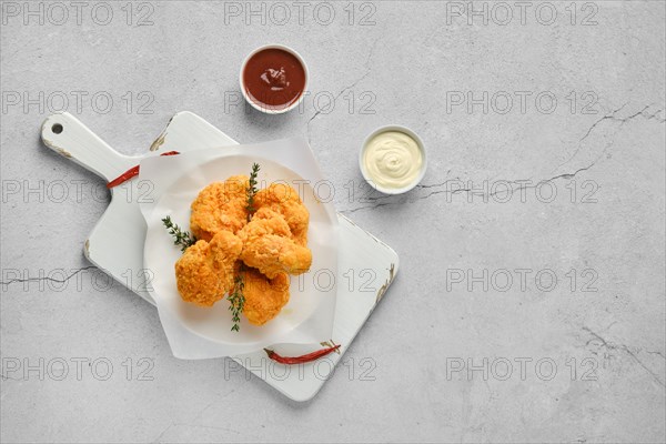 Top view of deep fried chicken in breading on white serving board