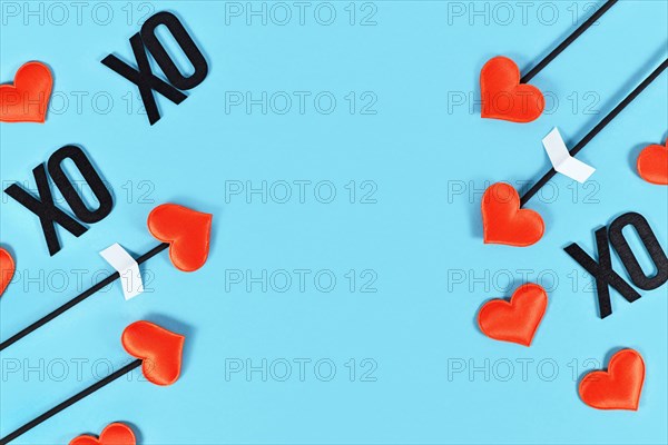 Valentine's day flat lay with cupid's love arrows and text XOXO on blue background with copy space