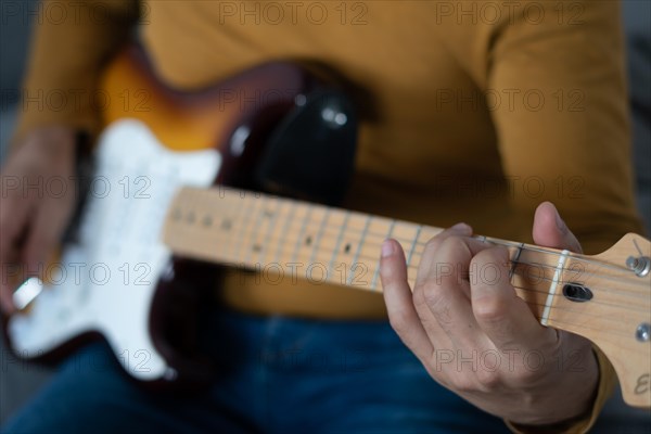 Young boy with beard playing guitar at home