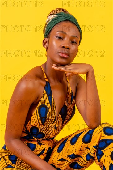 Young african woman with traditional costume on yellow background