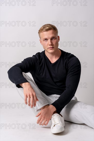 Caucasian blonde model in a black sweater on a white background