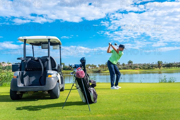 Man playing golf at golf club by a lake