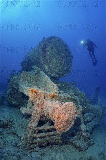 Remains of a steam locomotive from the Second World War on the seabed. Divers in the background. Dive site Thistlegorm wreck