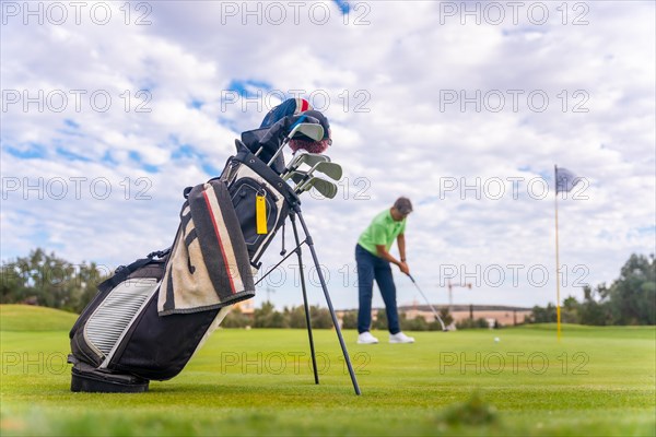 Caucasian professional golf player on the green preparing for the shot next to the fairway carrying bags