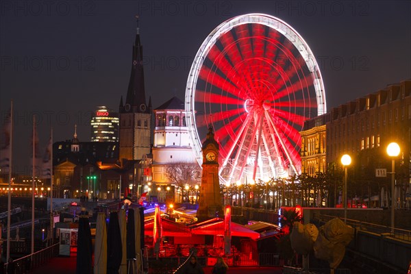 Rhine promenade with castle tower and illuminated Ferris wheel at dusk