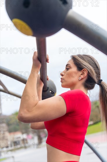 Fit woman in red outfit doing arm exercises on some bars
