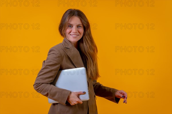 Portrait of a businesswoman with a computer or laptop on a yellow background