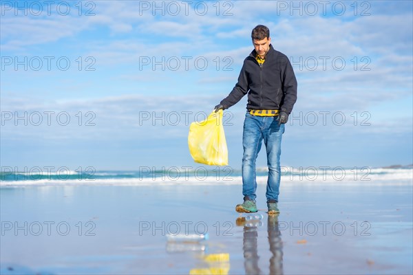 Volunteer man collecting garbage or plastic on the beach. ecology concept