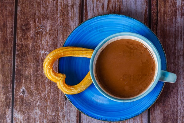 Hot chocolate with a churro in the form of a heart on a wooden table