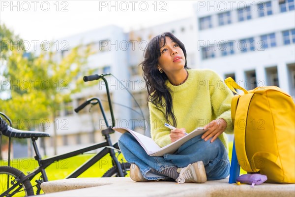 Asian female architecture student sitting in college campus making blueprint sketch