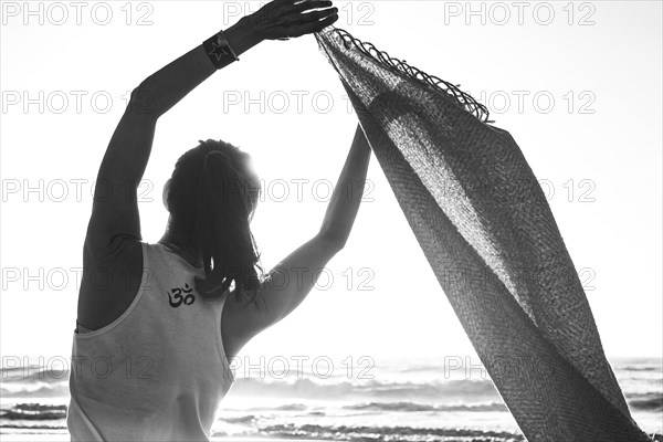 Rearview shot of a young woman with a t-shirt printed with an OM sign at the beach. Black and white photography