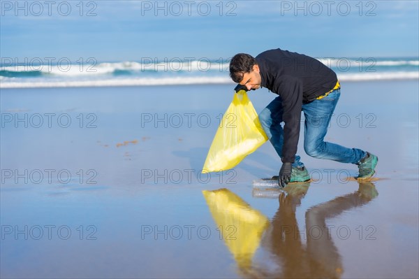 Man collecting garbage or plastic on the beach. Ecology concept