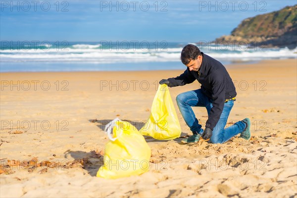 Volunteer person collecting plastic from the sand on the beach. Ecology concept