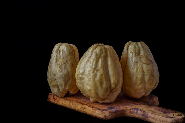 Chayotes isolated on a black background on a wooden board