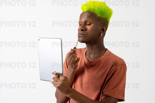 A gay black ethnic man putting on makeup