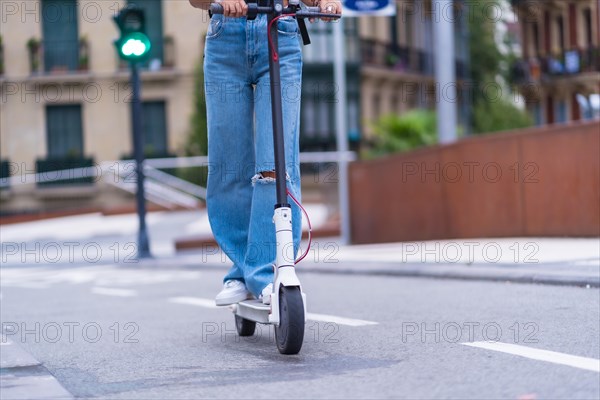 Detail of a young brunette woman moving in the city with an electric scooter