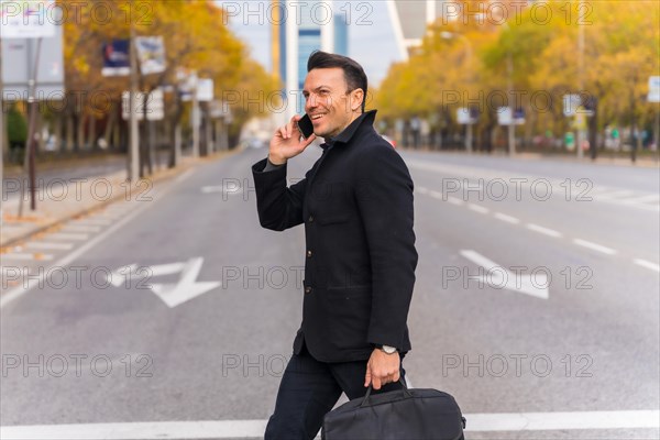 Middle-aged Caucasian businessman talking on the phone crossing the road in the city