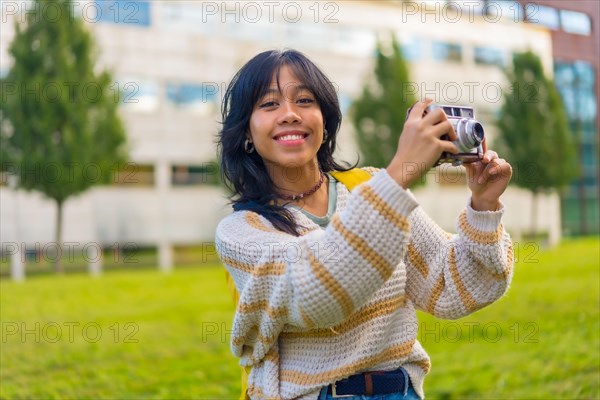 Portrait of a young Asian woman photographing with a vintage photo camera