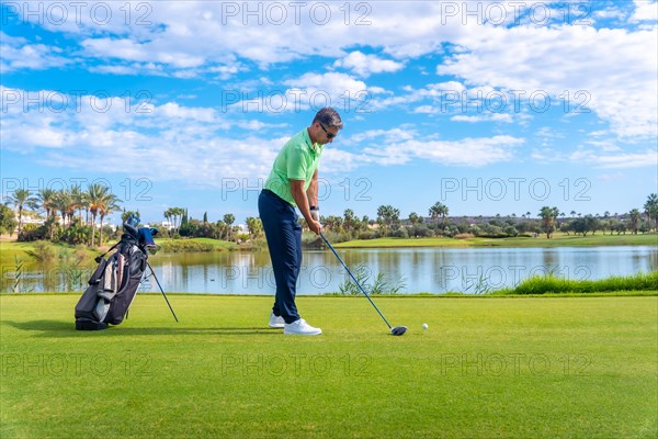 Male golf player on professional golf course. Golfer with driver stick by a lake