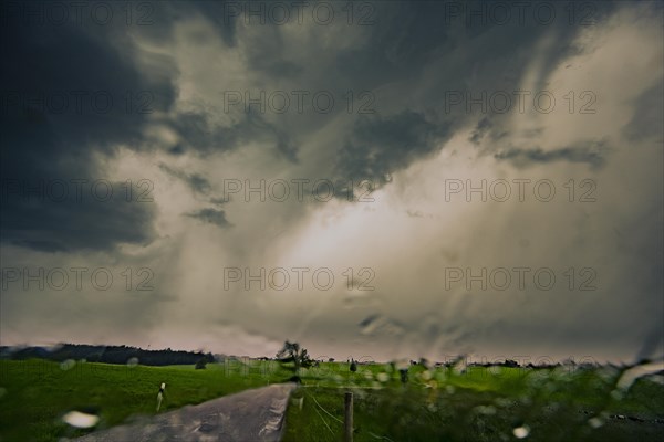 Road and meadows with thunderstorm sky in the background