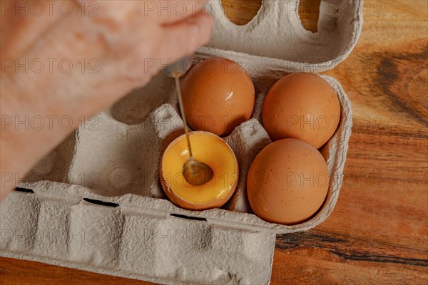Woman beating an egg in its own shell with a small blender
