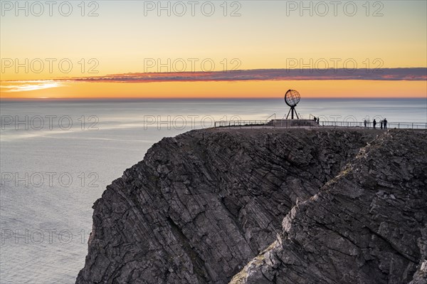 Rock cliff of the North Cape with steel globe at midnight sun