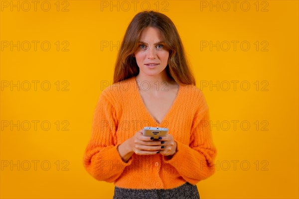 A woman looking at things on the internet on the mobile phone on a yellow background