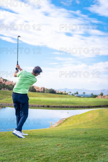 Man playing golf at golf club by a lake