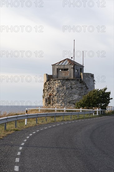 Coastal road and ruins of the historic lighthouse in the evening light on the cliff on Pakri Peninsula