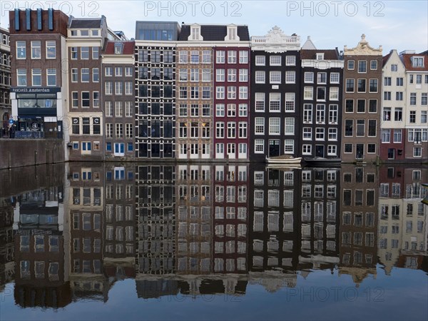 Row of typical houses with reflection in Damrak