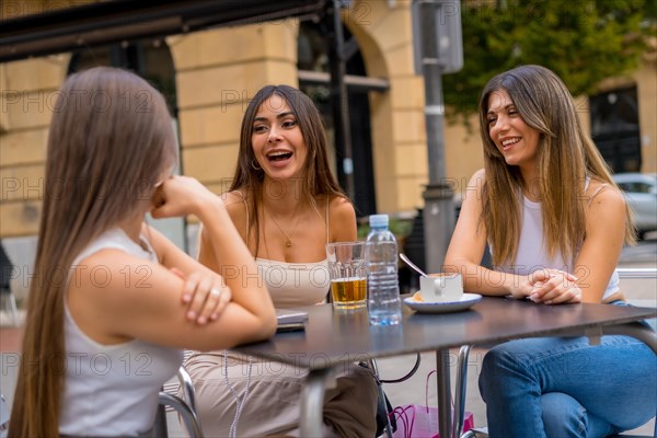 Portrait of young women friends having something one afternoon on a terrace of a cafeteria in autumn