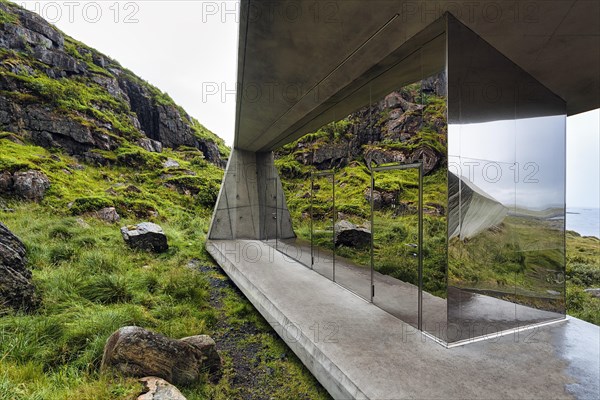 Mirrored toilet block on rocky coast