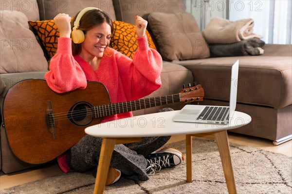 Woman learning to play the guitar at home with online classes on the computer