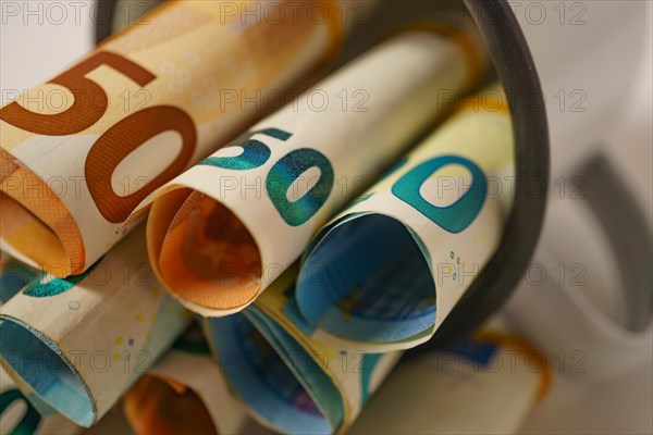 Rolled euro banknotes in a white cup with white background and copy space