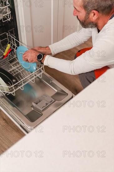 Man in white t-shirt putting the dishes in the dishwasher