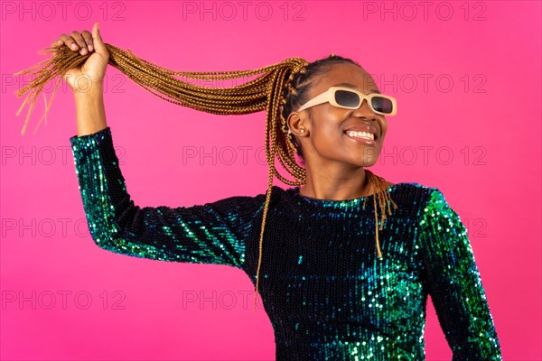 A black ethnic woman with braids party dancing on a pink background