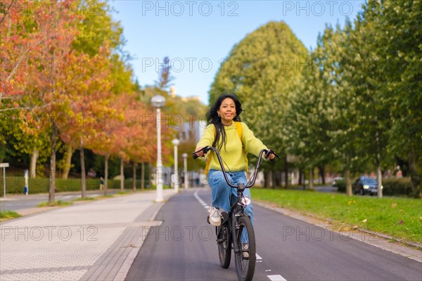 Young Asian female student riding a bicycle on her way to university along the bike lane