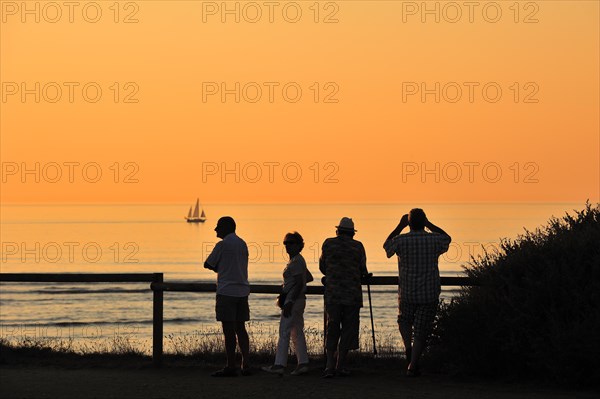 Tourists looking at sailing ship at sunset at Saint-Denis-d'Oleron on the island Ile d'Oleron
