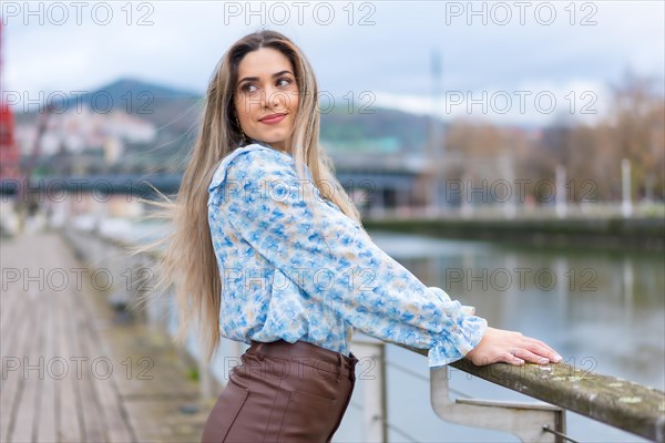 Portrait of young woman walking along the river in the city