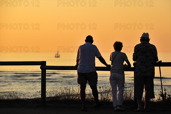 Tourists looking at sailing ship at sunset at Saint-Denis-d'Oleron on the island Ile d'Oleron