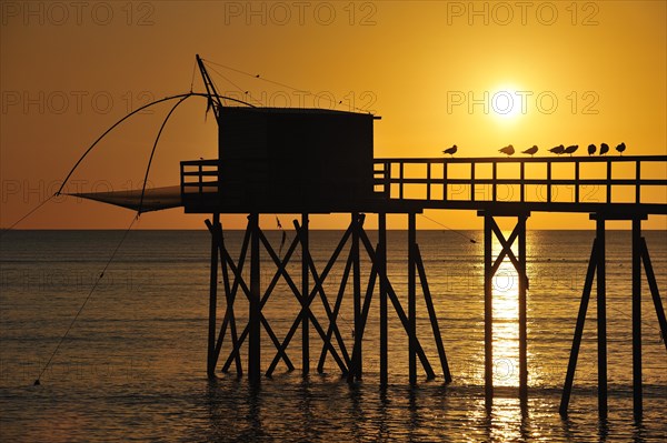 Traditional carrelet fishing hut with lift net on the beach at sunset