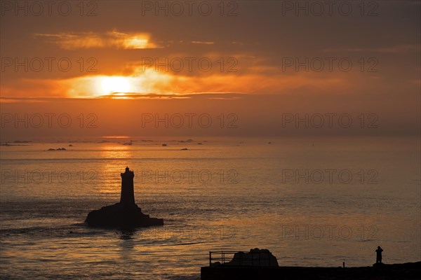 The lighthouse La Vieille in the strait Raz de Sein silhouetted against sunset at the Pointe du Raz