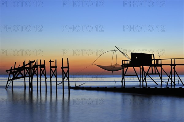 Traditional carrelet fishing hut with lift net on the beach at sunset