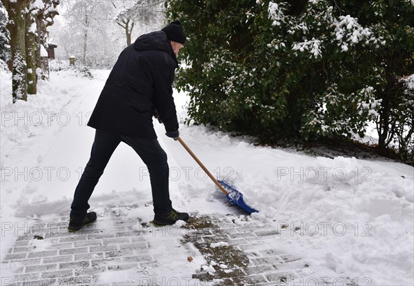 Man pushing snow on pavement