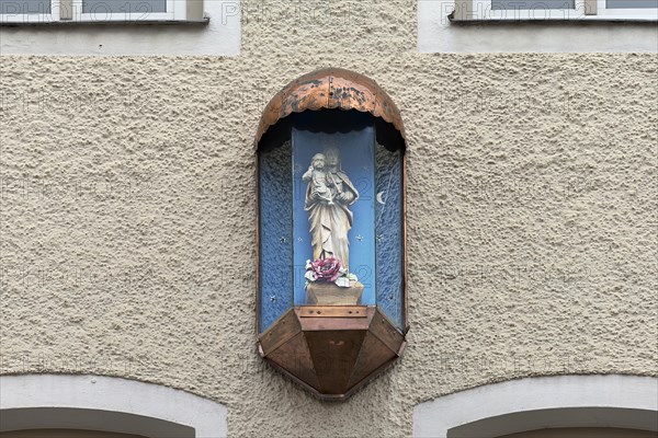 Sculpture of the Virgin Mary in a glass case on a residential house