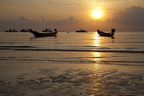 Thai fishing boats silhouetted against sunset