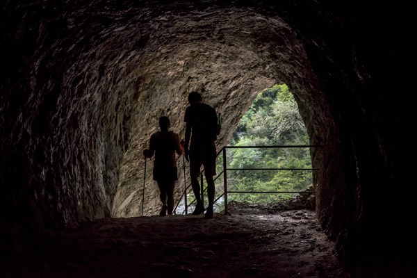Two walkers leaving tunnel on the Sentier Martel path in the Gorges du Verdon